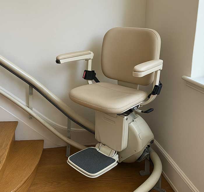 Treppenlift an steiler Holztreppe mit beigem Sitz